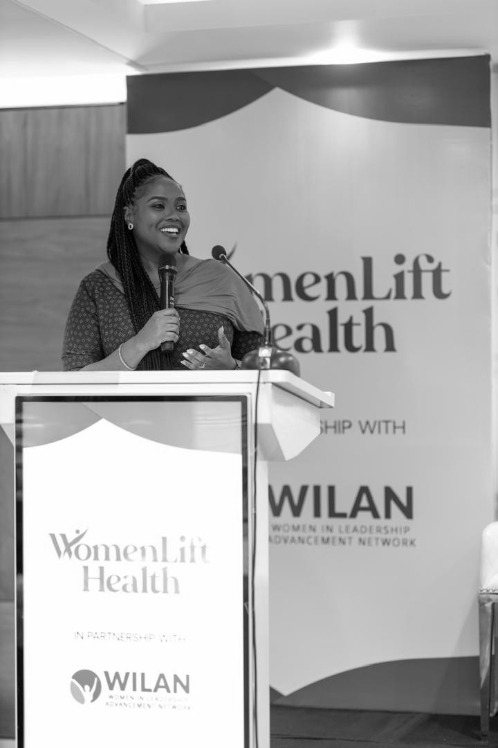 Abosede George-Ogan speaking at a WILAN and WomenLift Health lectern, in black and white